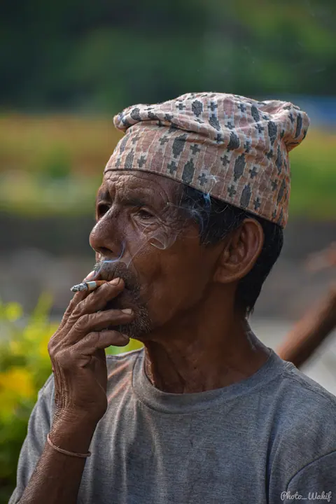 Portrait of an older Nepali man wearing a traditional topi.