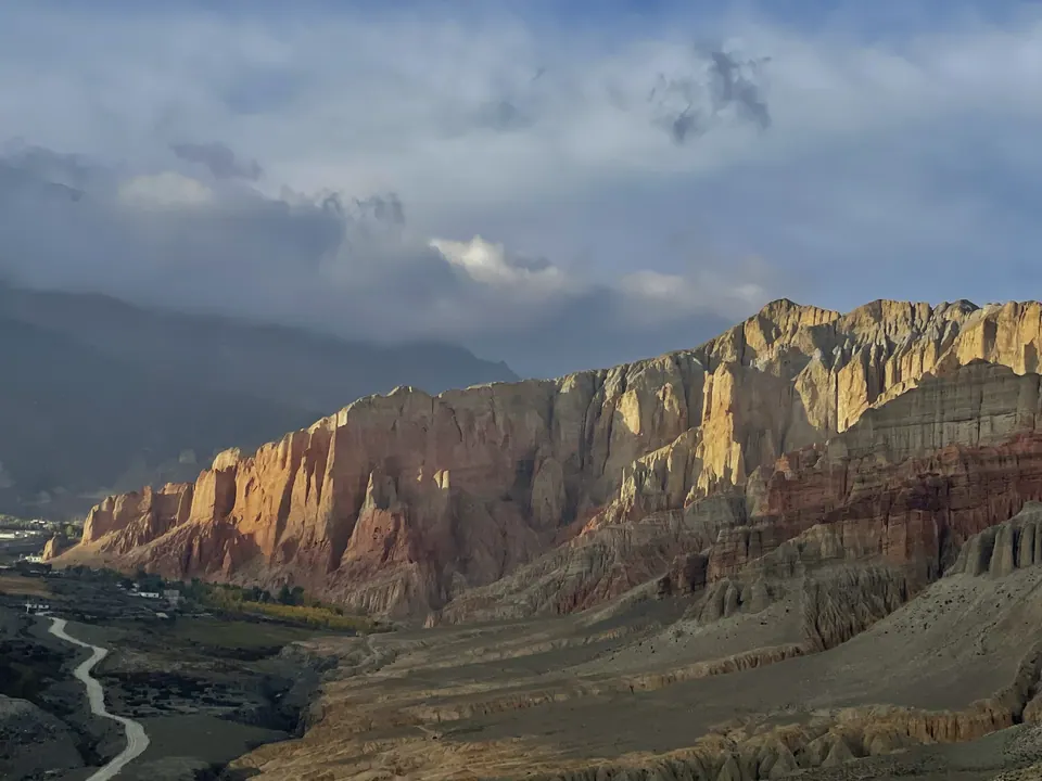 Sunlight striking banded cliffs above a mountain river.
