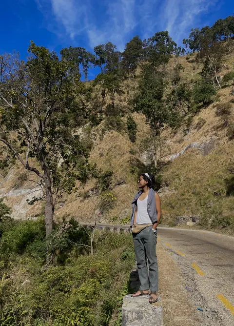 A lone walker on a mountain road between forested slopes.