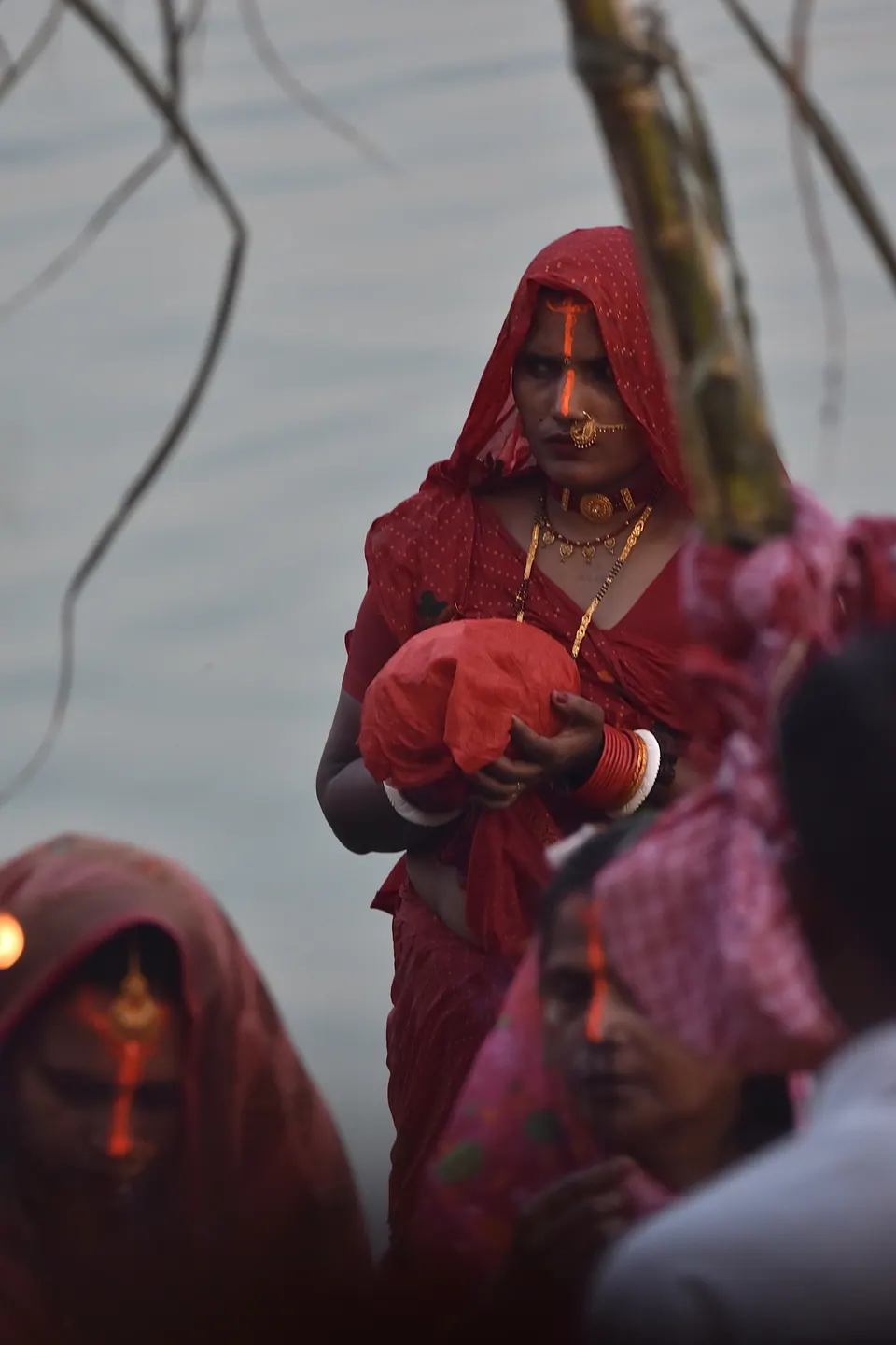 Women in red clothing gathered beside water.