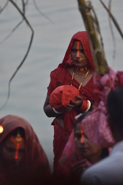 Women in red clothing gathered beside water.