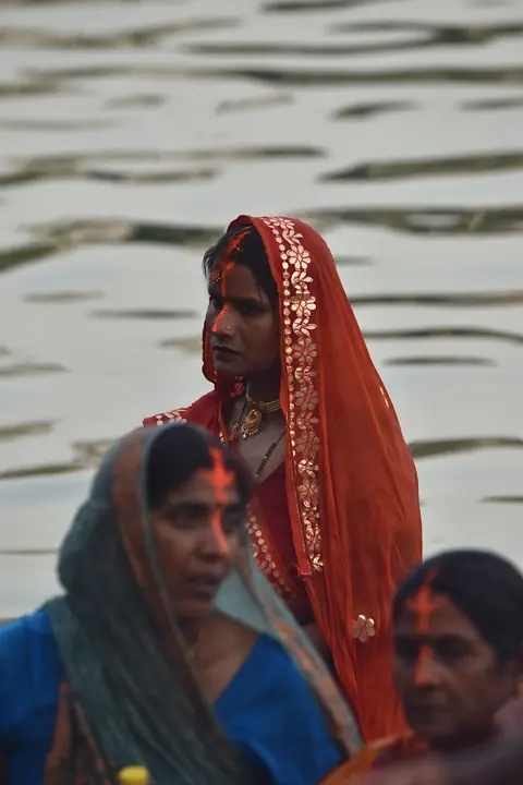 Women gathered in traditional dress beside the river.