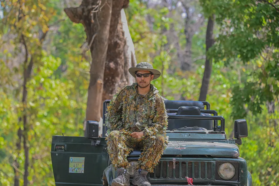 A field guide seated on the front of a safari jeep.