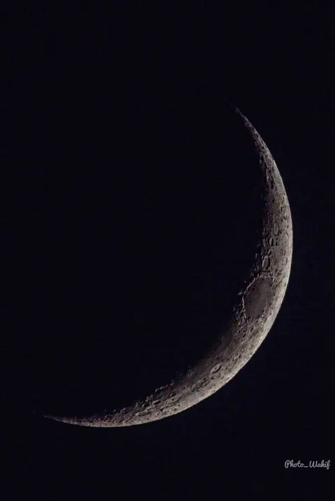 A fine crescent moon in a black sky.