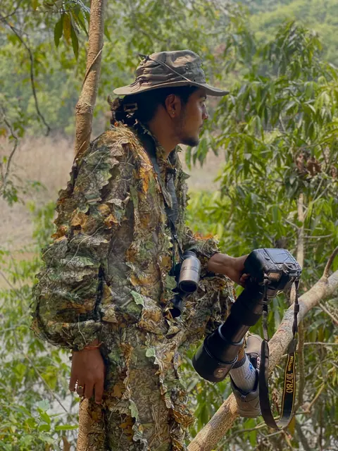 A nature photographer with a long lens in the forest.