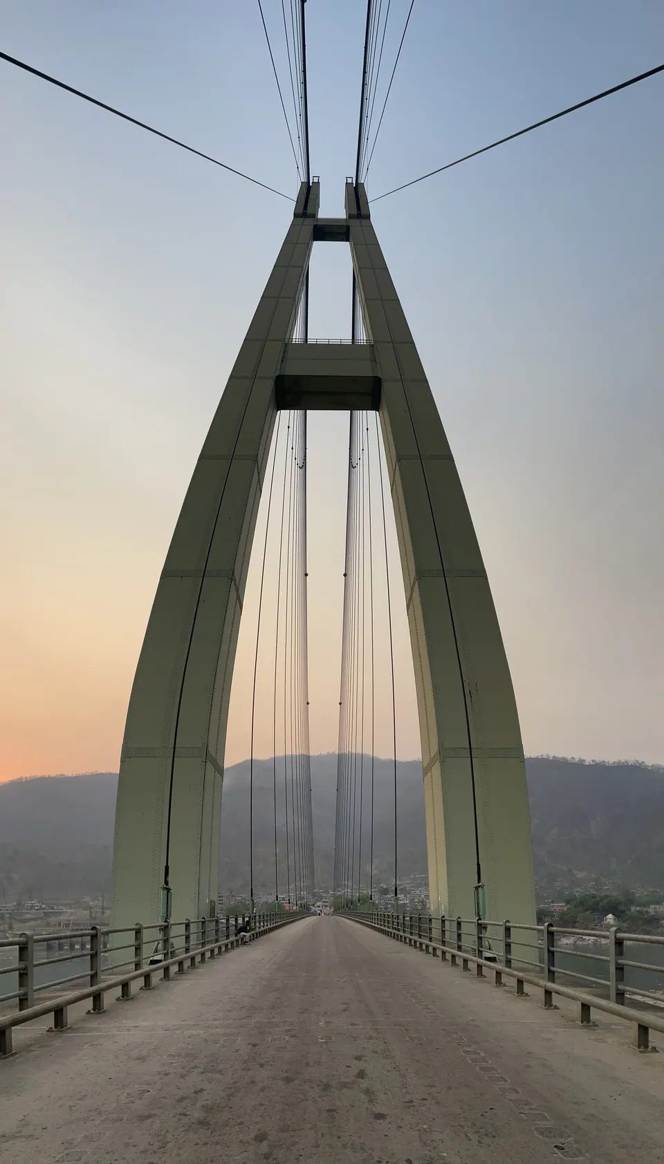 A long suspension bridge reaching toward the hills.