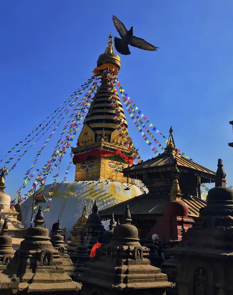 A historic Nepalese stupa beneath a clear blue sky.