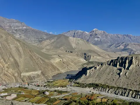 A wide Himalayan valley beneath a clear blue sky.