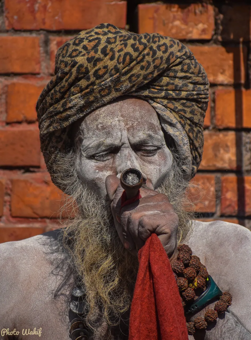 Portrait of a sadhu in layered robes and beads.