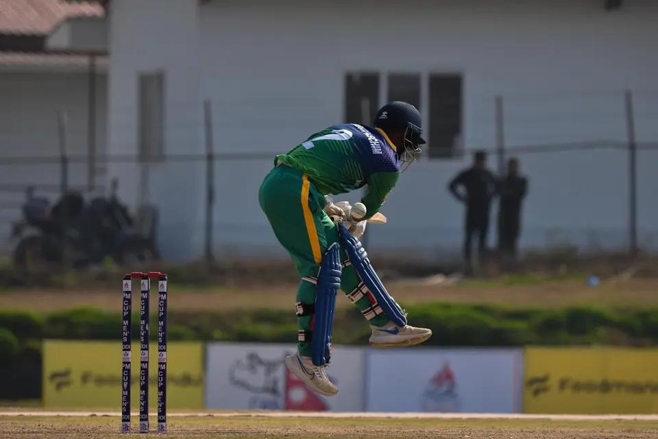A cricket bowler releasing the ball in competition.