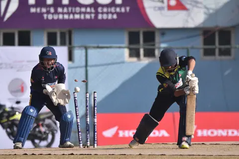 A women's cricket match photographed from beside the wicket.
