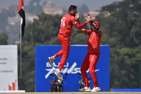A bowler driving through the crease.