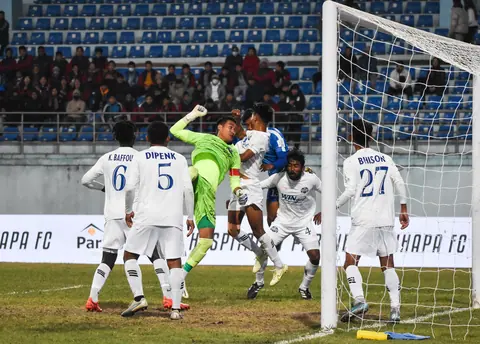 Football players contesting the ball in front of goal.